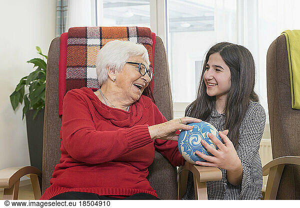 Girl playing bowling with senior woman in rest home