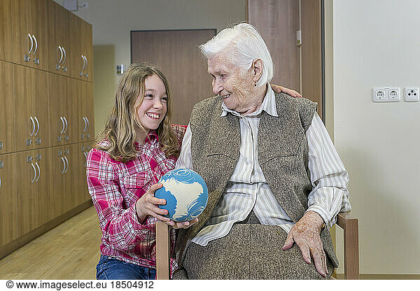 Girl playing bowling with senior woman in rest home