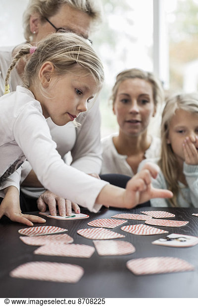 Girl playing card puzzle game with family at home