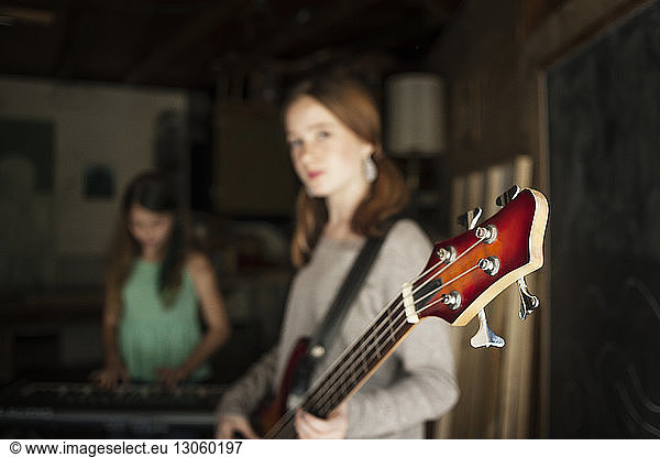 Girl playing guitar with friend in background