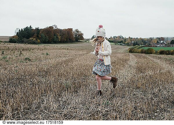 girl playing in a field on a windy day in the countryside