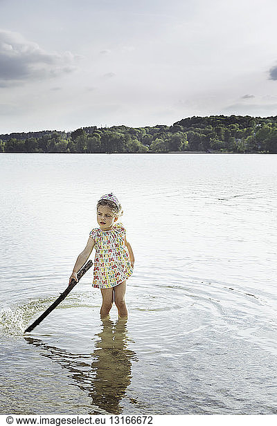 Girl playing in lake with stick  Munich  Bavaria  Germany