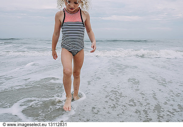 Girl playing in waves at Cape May Beach against sky