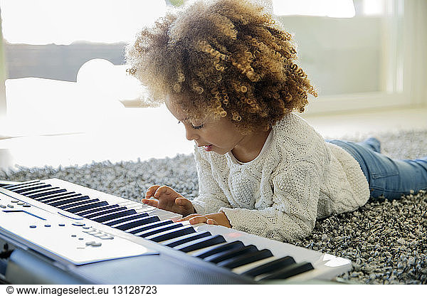 Girl playing keyboard instrument on carpet at home
