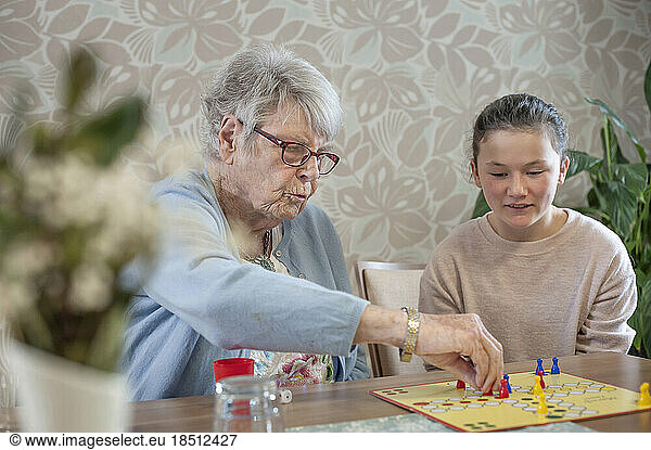 Girl playing ludo board game with senior women in rest home