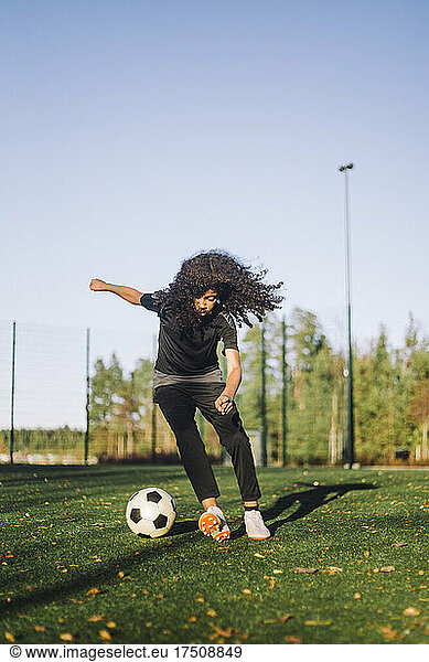 Girl playing soccer on sports field during sunny day