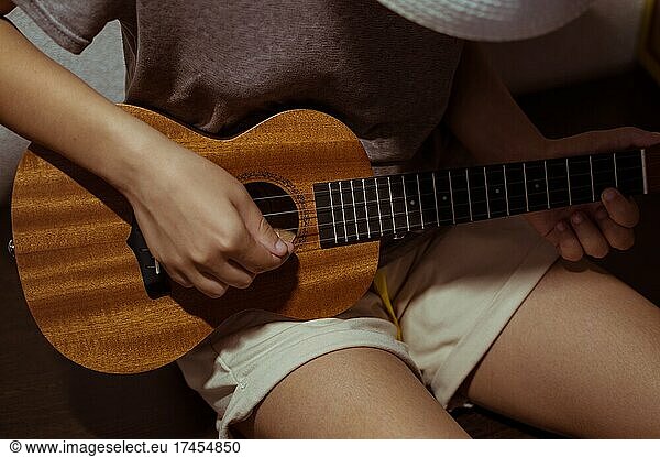 Girl playing ukulele bent over  close-up