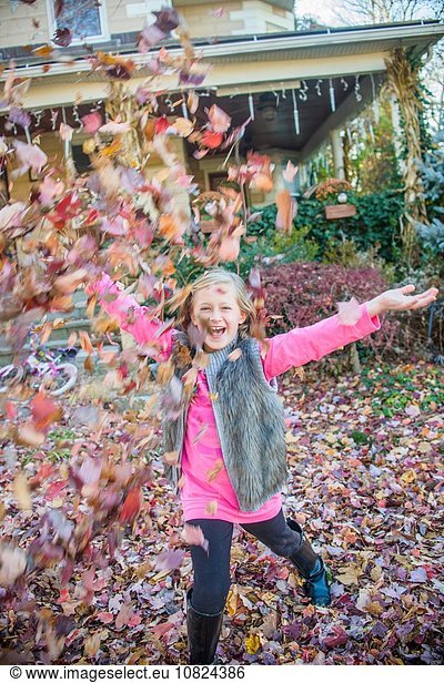 Girl playing with autumn leaves in garden
