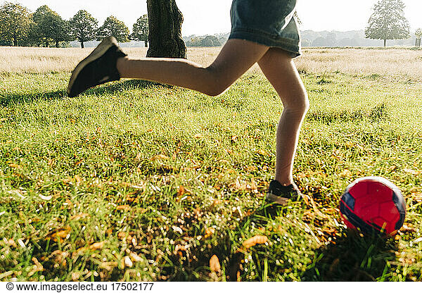 Girl playing with ball in park on sunny day