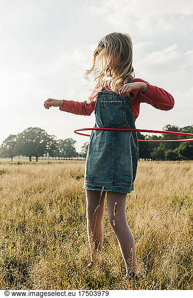 Girl playing with hula hoop in park at weekend