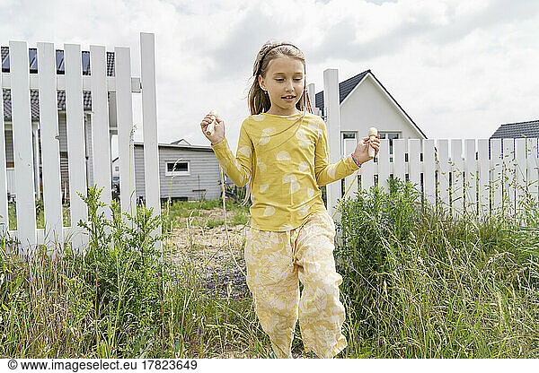 Girl playing with jump rope in backyard