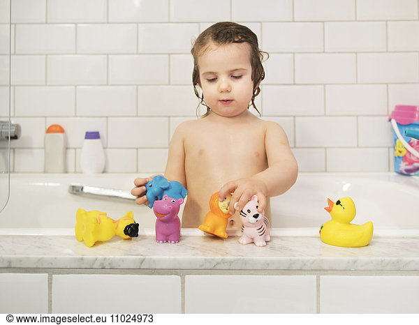 Girl playing with rubber toys in bathtub