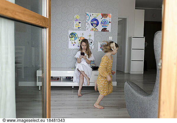 Girl playing with sister using smart phone in background
