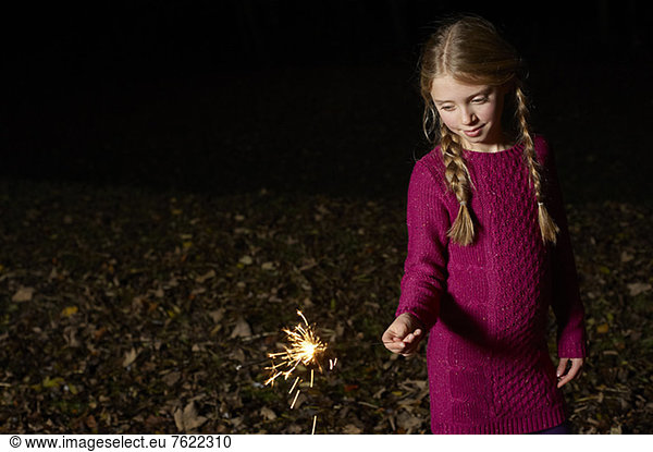 Girl playing with sparkler outdoors