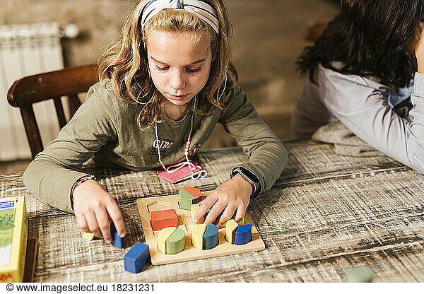 Girl playing with toy blocks at table in home