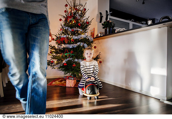 Girl playing with toy car against decorated Christmas tree at home