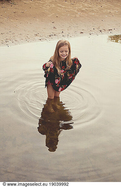 Girl plays in the lake in the morning light