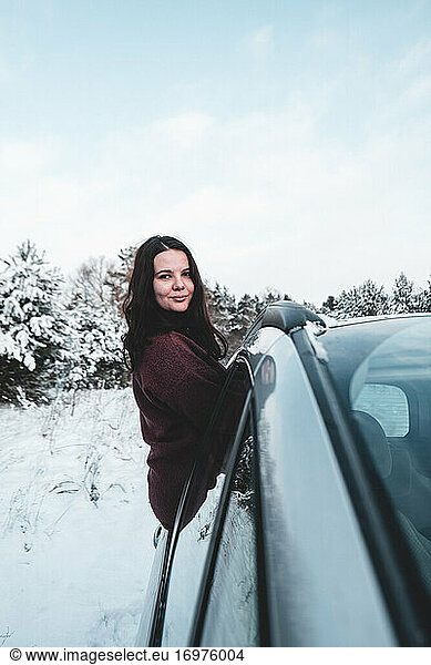 Girl posing on a car door on a beautiful snowy day