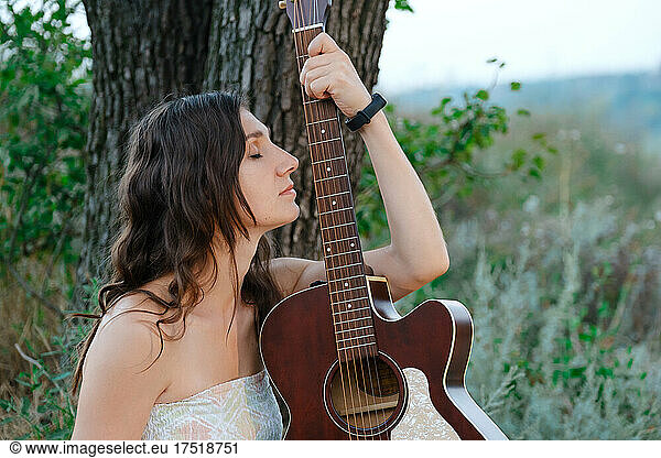 Girl posing with guitar. Romantic pretty girl sitting with guitar.