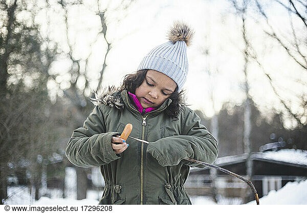 Girl putting food on stick during winter