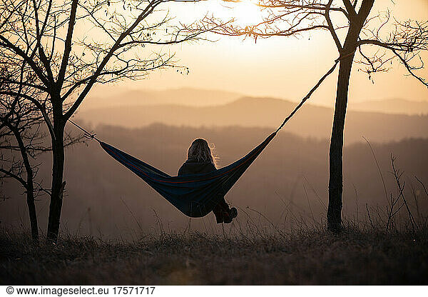 Girl relaxing on hammock in the nature during sunset