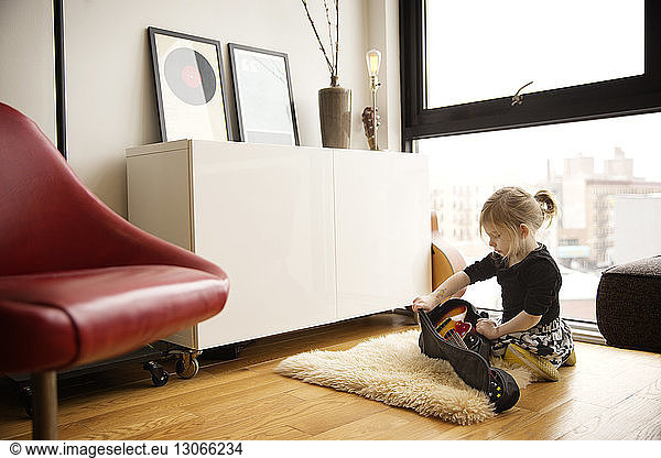 Girl removing guitar from case while sitting at home