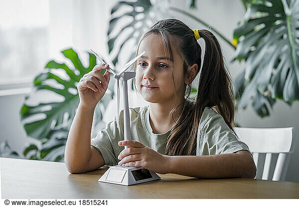 Girl rotating wind turbine model at home