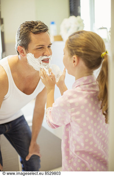 Girl rubbing shaving cream on father's face