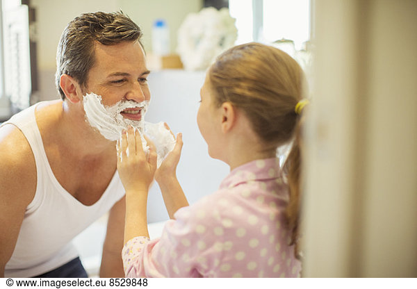 Girl rubbing shaving cream on father's face