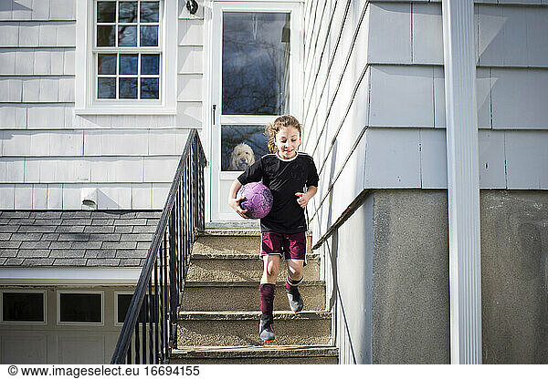 Girl running down stairs with soccer ball