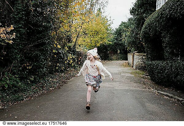 girl running through the streets joyfully in Autumn Uk