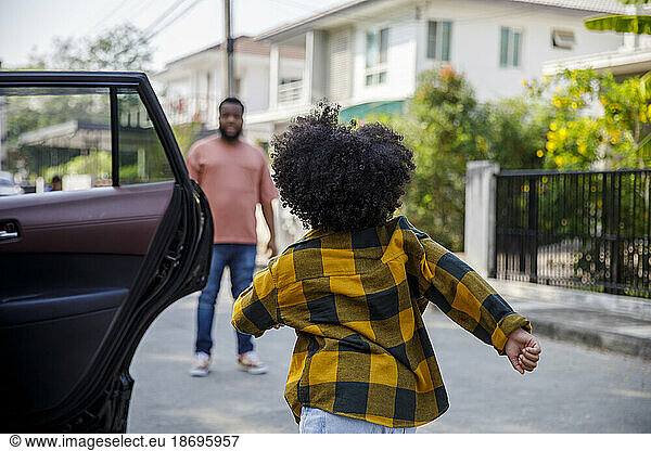 Girl running towards father standing on road