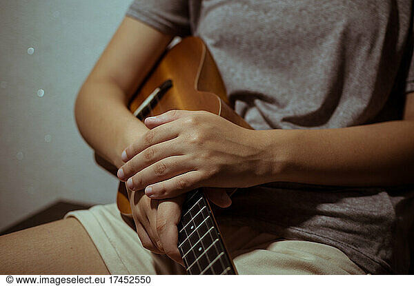 Girl's hands folded on wooden ukulele  close-up