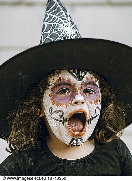 Girl screaming with face painted and disguised for halloween
