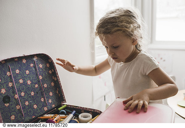 Girl searching for toys in suitcase at playroom