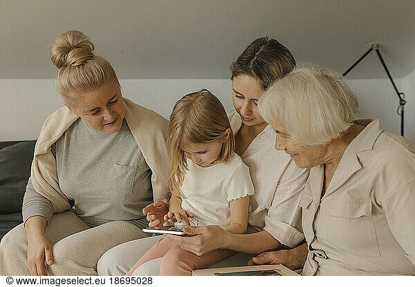 Girl sharing tablet PC with family sitting at home