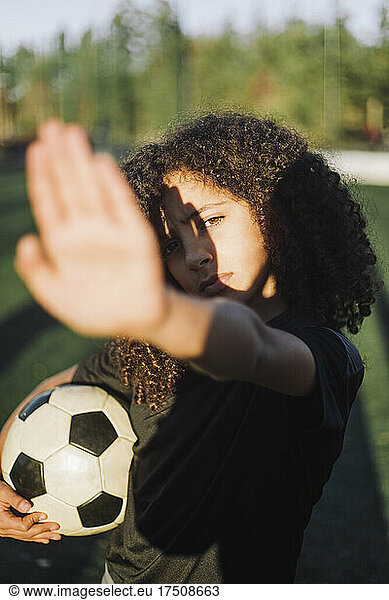 Girl shielding eyes from sunlight on sports field