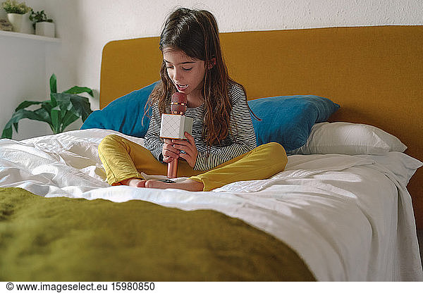 Girl singing with micro and using smartphone on bed