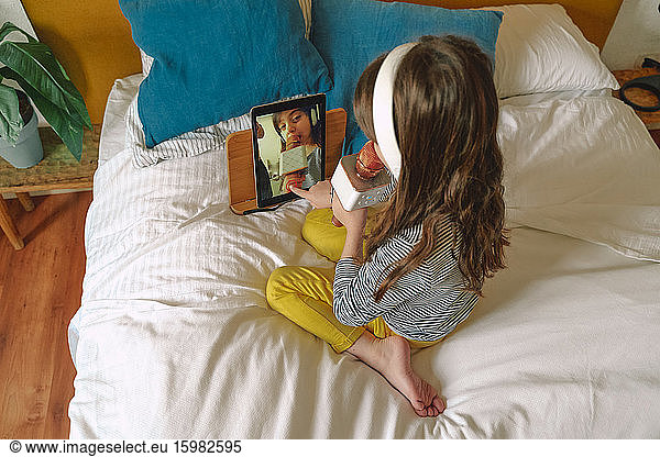 Girl singing with micro and using tablet for a video on bed
