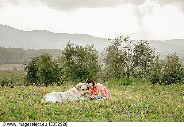 Girl sitting and petting labrador dog in scenic field landscape  Citta della Pieve  Umbria  Italy