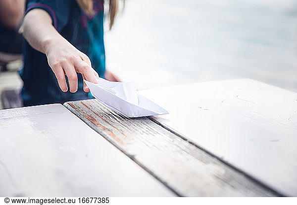Girl Sitting By The Sava River Playing With A Paper Boat