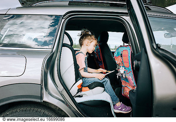 girl sitting in the car drawing pictures feeling happy