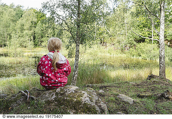 Girl sitting near lake in tranquil forest