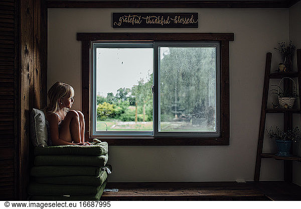Girl sitting on chair by window at home
