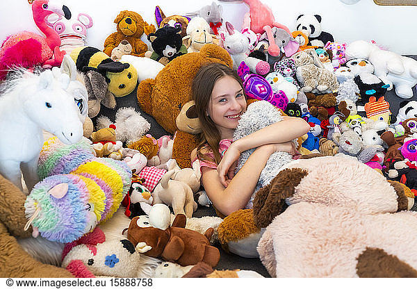 Girl sitting on couch  covered in cuddly toys
