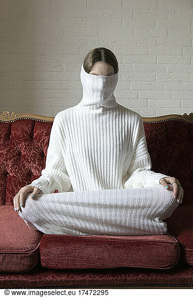 Girl sitting with covered face from turtleneck dress
