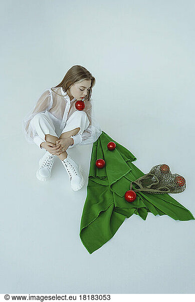 Girl sitting with eyes closed by abstract Christmas tree against white background