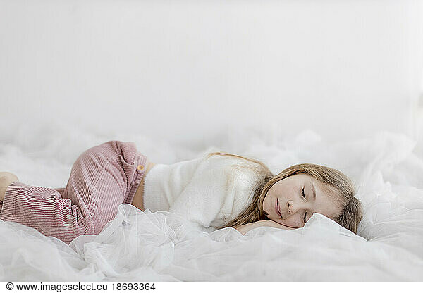 Girl sleeping in front of white wall