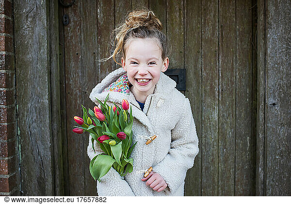 girl smiling holding flowers whilst walking outside