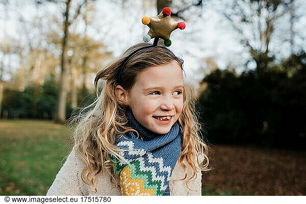 Girl smiling with a Christmas star headband playing outside